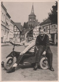Zwei Jungen mit Dreirad auf Dorfstraße