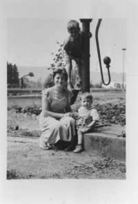 Frau Claire Bleffert mit ihren Kindern sitzt am Sauerbrünnen hinter dem Bahnhof